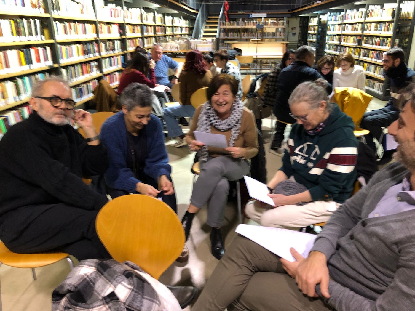 Un gruppo seduto in cerchio fra gli scaffali di una biblioteca, con le schede dell'esercitazione in mano